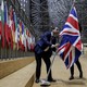 A person removes the British flag from a hall with European flags.