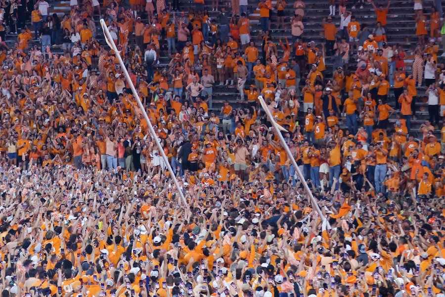 A huge crowd of football fans pulls down a goalpost.