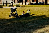 A father and small child relax on the grass.