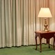 A lamp on a table in a corner of a funeral parlor room