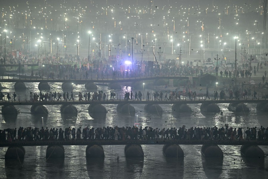 Many people walk across multiple pontoon bridges over a river.