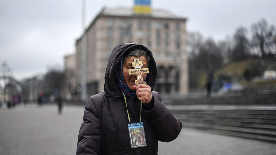 A religious woman holds a cross as she prays on Independence Square in Kyiv.