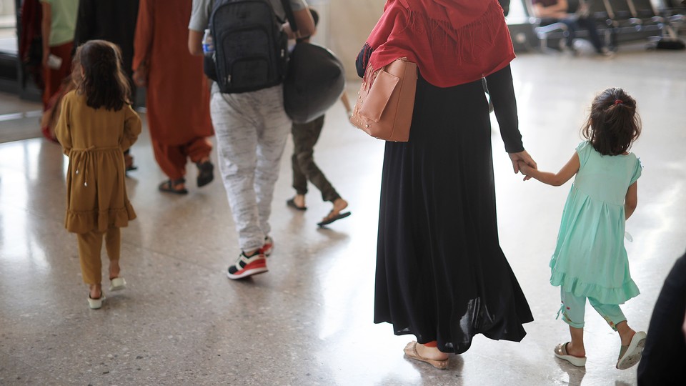 Parents walk with their young children through an airport