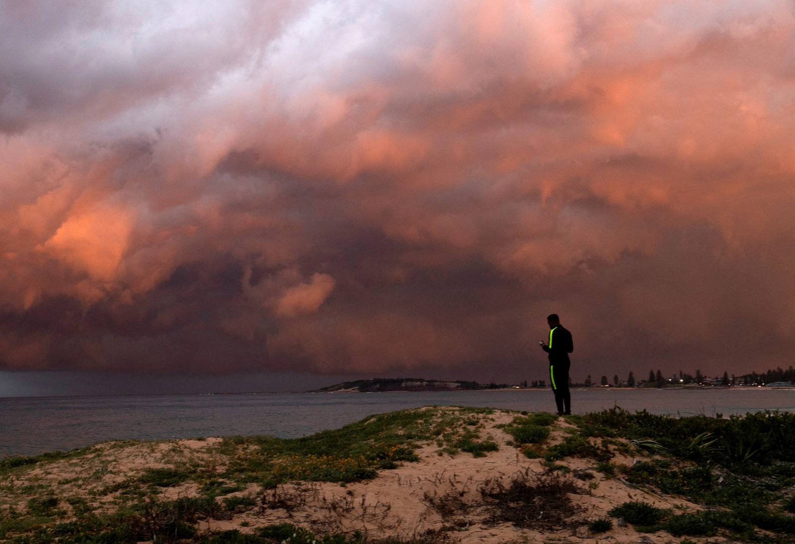 A man watches a storm sweep across a harbor.