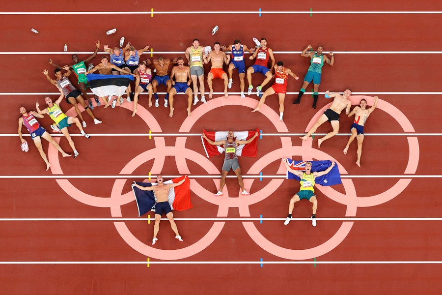 Decathletes lie on a track, looking up toward an overhead camera.