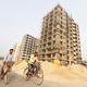 Men ride their bicycles past residential buildings under construction on the outskirts of Kolkata, India, on February 1, 2017.