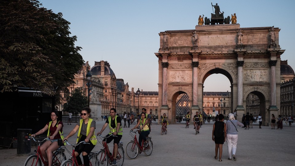 Cyclists stream past the Arc de Triomphe du Carrousel in Paris.