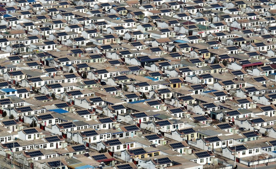 An aerial view of a dense neighborhood full of houses with solar panels on their roofs