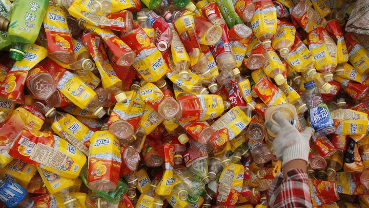 A worker picks up a plastic bottle as she separates them at a recycling depot in Beijing.
