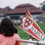 A girl holds a Harvard pennant.