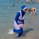 A woman wearing a burqini walks in the water on a beach in France.