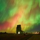 The northern lights illuminate the sky over an old grain elevator.