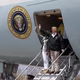 Donald and Melania Trump wave from the stairs of a plane.