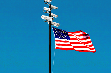 A flagpole with surveillance cameras at the top and an American flag waving