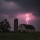 An image of a barn, with lightning striking over it. 