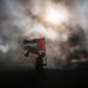 A demonstrator surrounded by smoke holds a Palestinian flag
