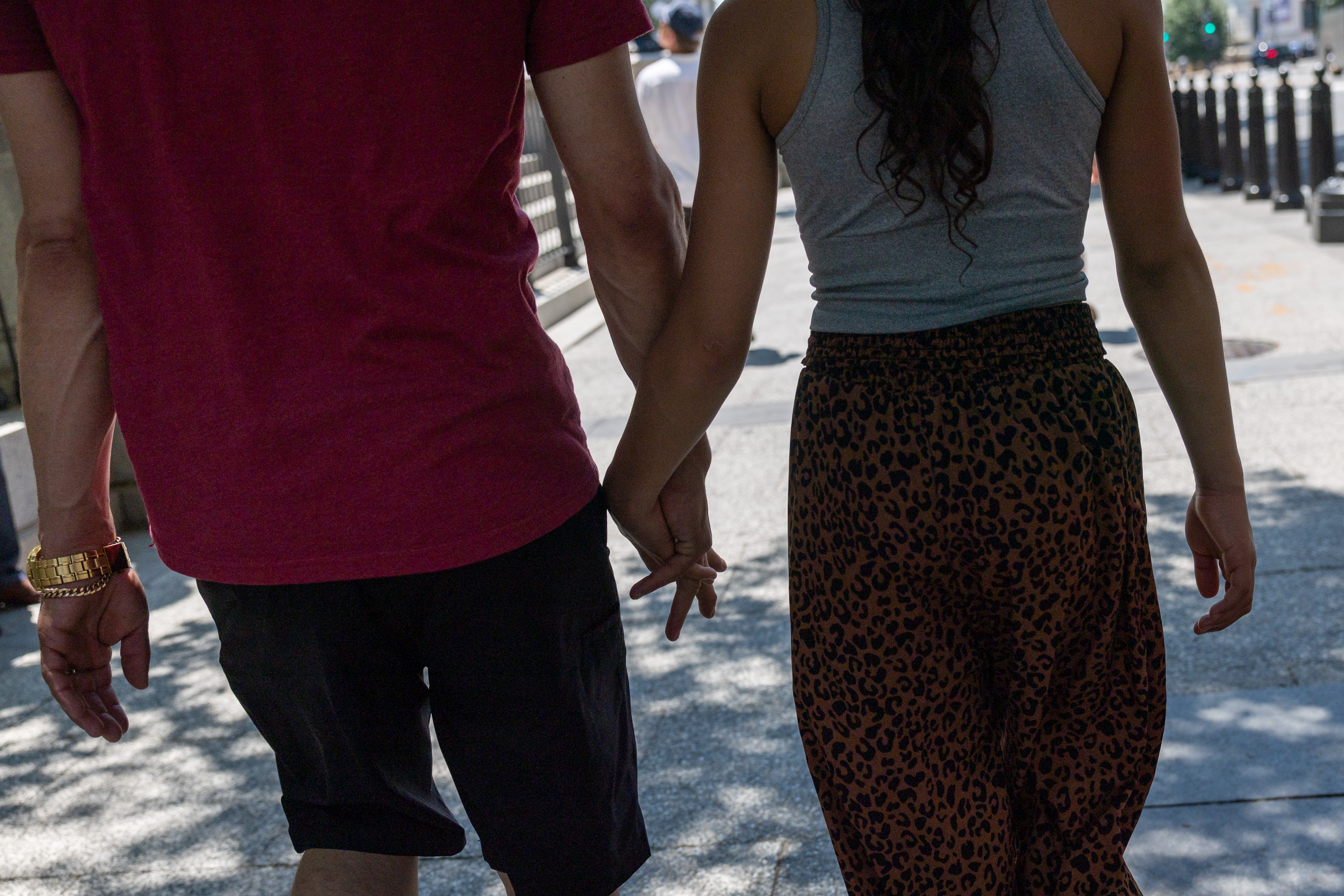 A father and daughter hold hands while walking.