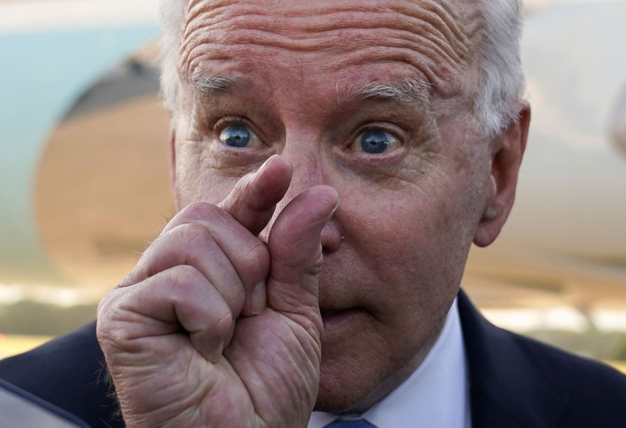 President Biden makes a gesture with his thumb and forefinger in front of his face, indicating something very small.