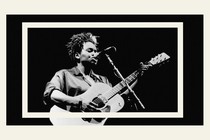 A black-and-white image of Tracy Chapman playing the guitar and singing.
