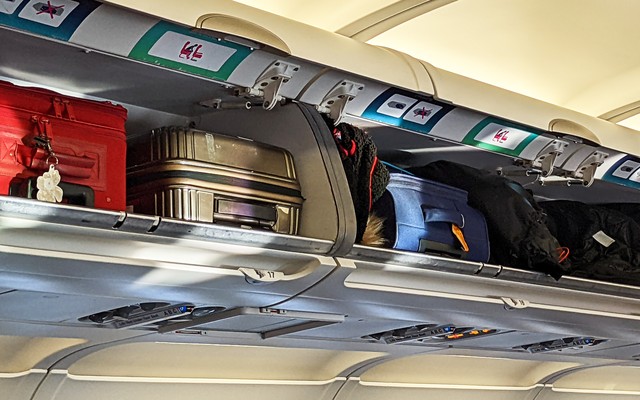 Suitcases packed into an airplane's overhead luggage bins