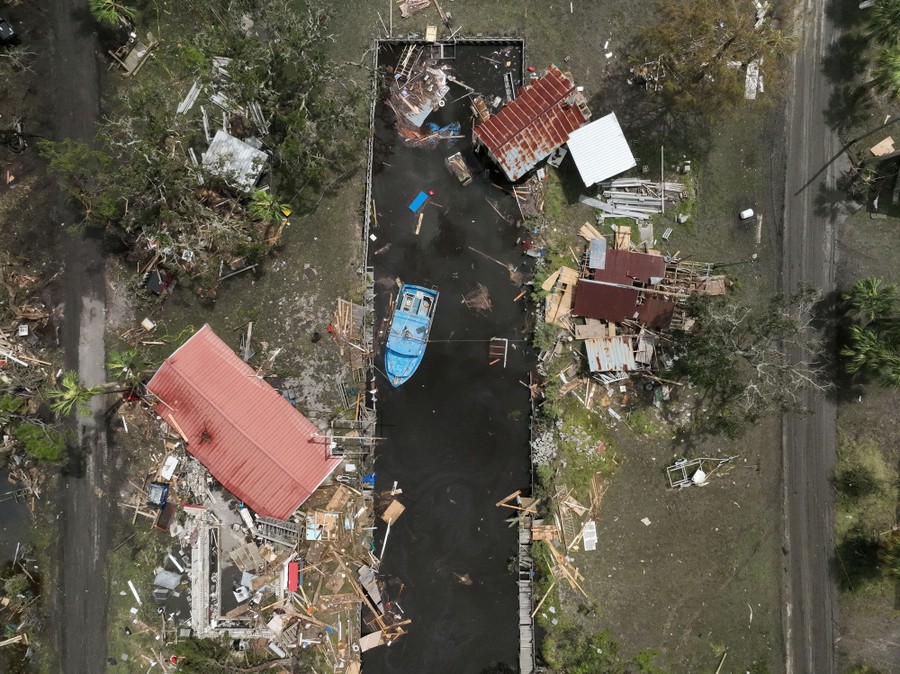Debris from storm-battered houses and outbuildings along a canal