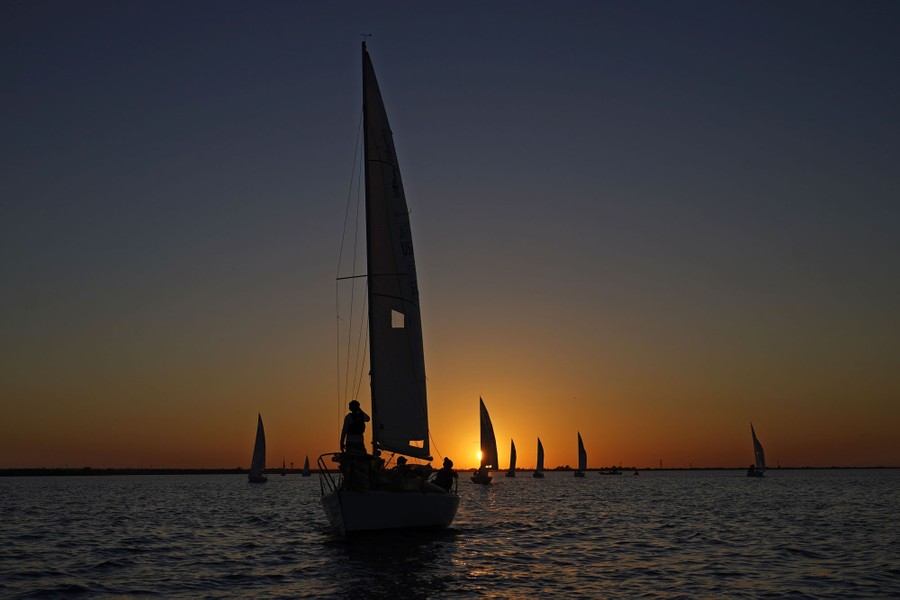Sailboats are seen on a lake at sunset.