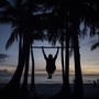 The silhouette of a man doing a pull-up on a beach in the Philippines.