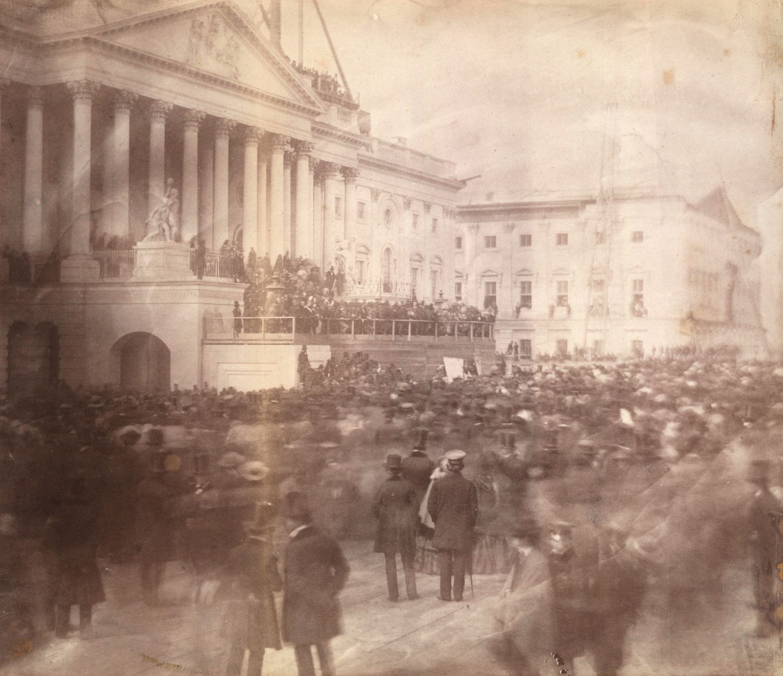 An older photograph showing a crowd (looking blurry due to movement) in front of the U.S. Capitol building during an inauguration ceremony.