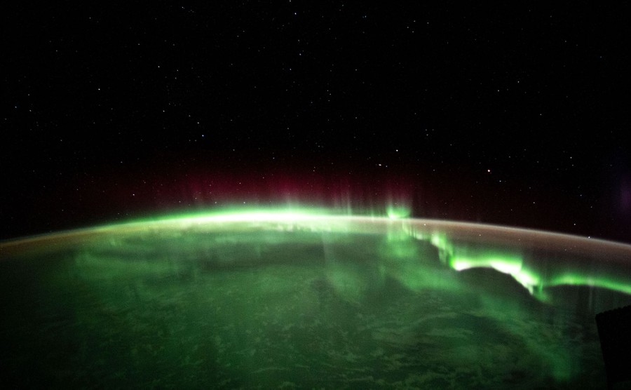 Green shimmers of light are seen above the Earth at night.