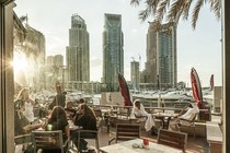 Photograph of outdoor seating at a restaurant in Dubai with the sun shining on diners