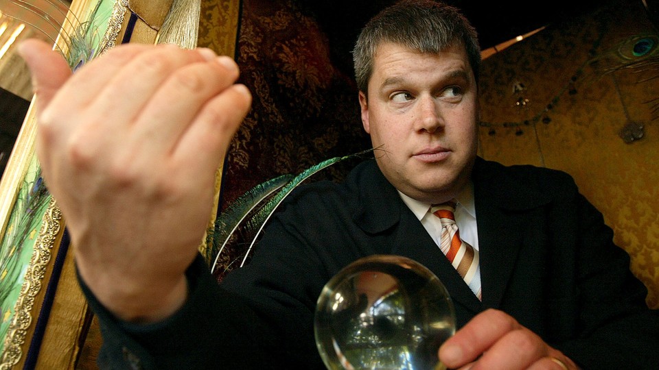 A man wearing a suit, holding a crystal ball, and looking furtively out of the corner of his eyes beckons with his hand