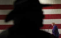 Trump speaking in front of a shadow over the American flag