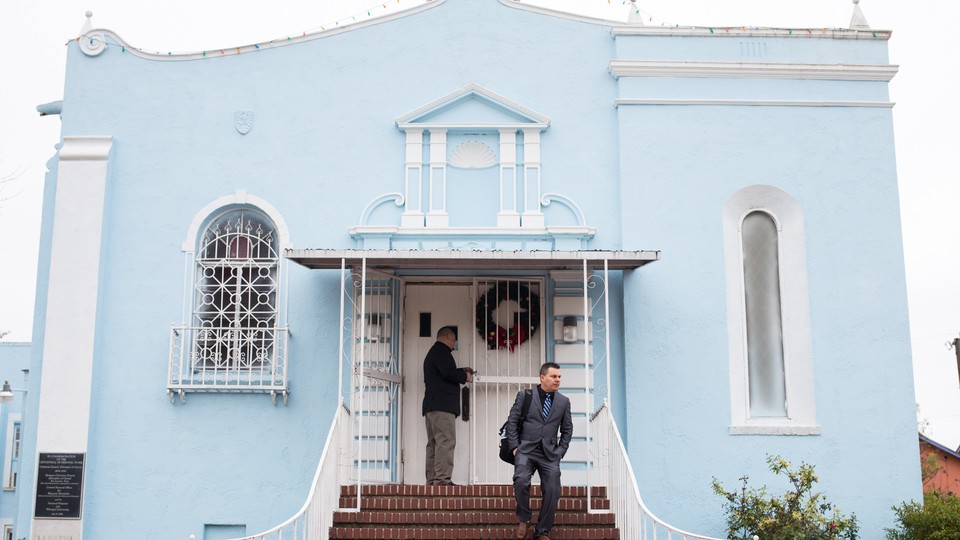 A pastor exits a blue church.