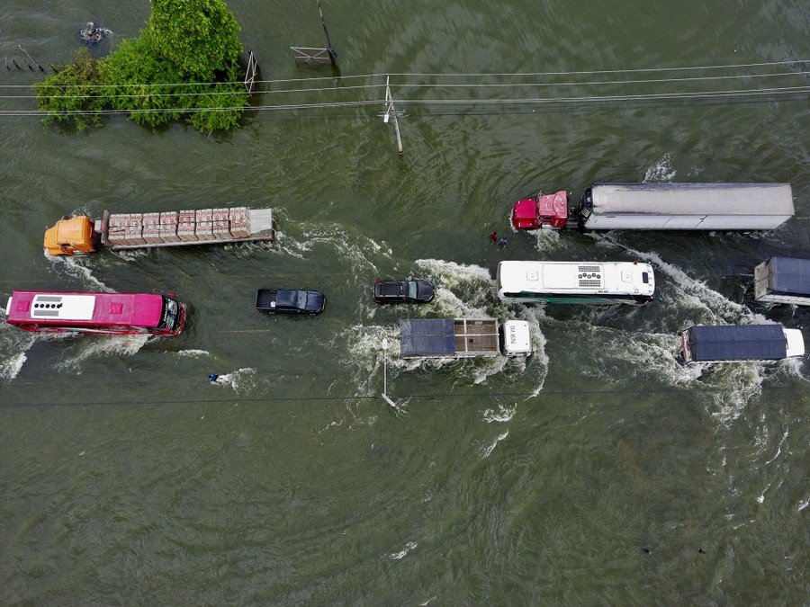 An aerial view of cars and trucks driving on a fully flooded road