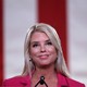 Photo of Pam Bondi smiling at a microphone, with a large American flag behind her
