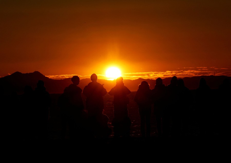 People greet the first sunrise of the year on a beach.