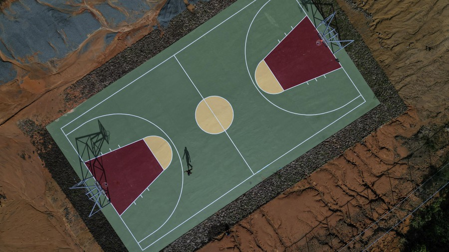 A person walks on a new basketball court, seen from above.