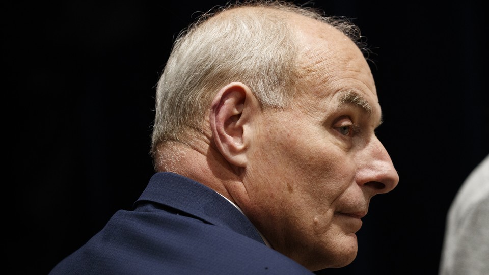 Former White House Chief of Staff John Kelly is seen in profile. The background behind him is black and he's wearing a navy suit.