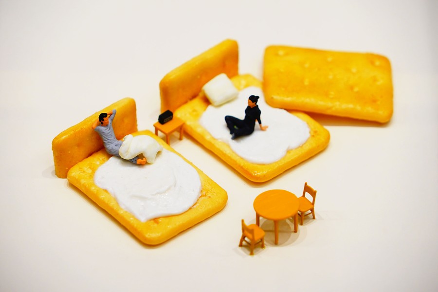 A miniature diorama, featuring models of people on beds made of crackers.