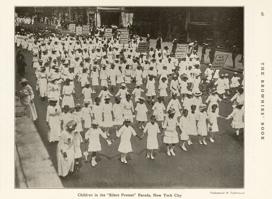 Black dhildren dressed in white marching in a parade