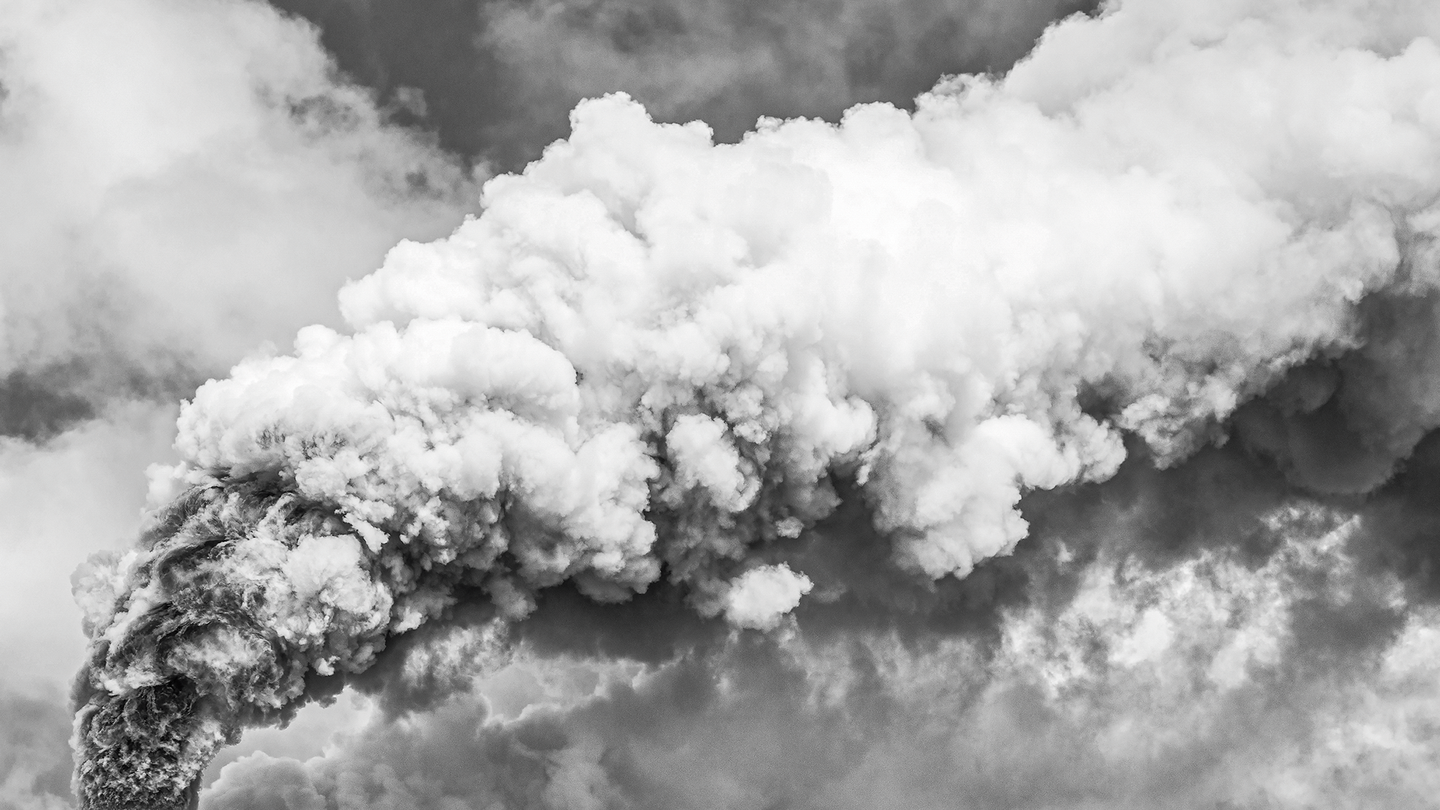 Fotografía en blanco y negro de humo saliendo de una chimenea.
