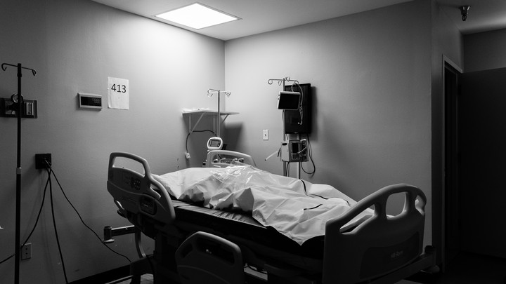 A hospital bed with a deceased patient in a body bag