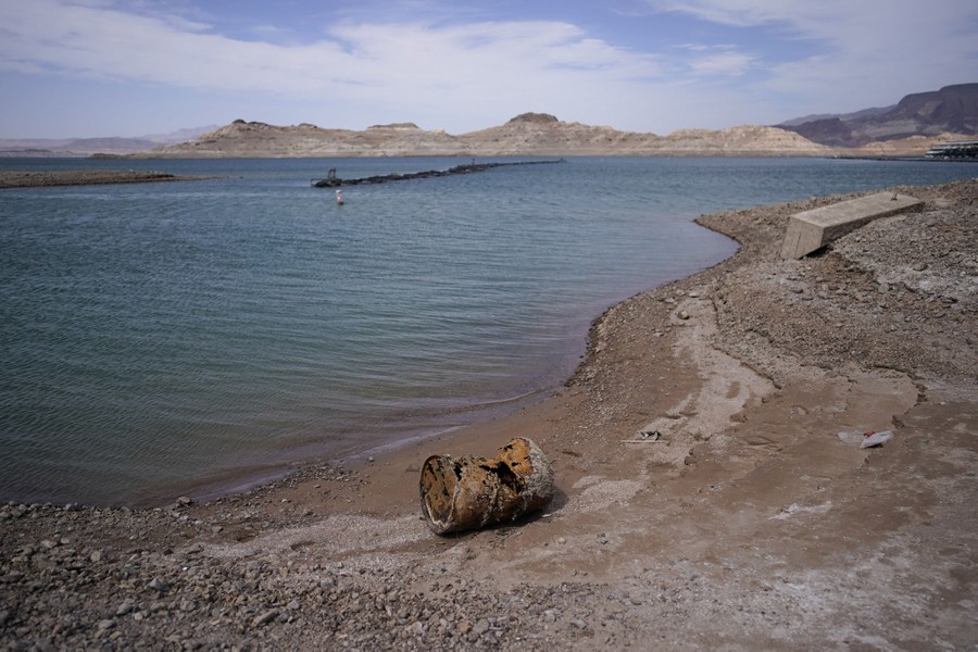 A rusting barrel sits on a shoreline.