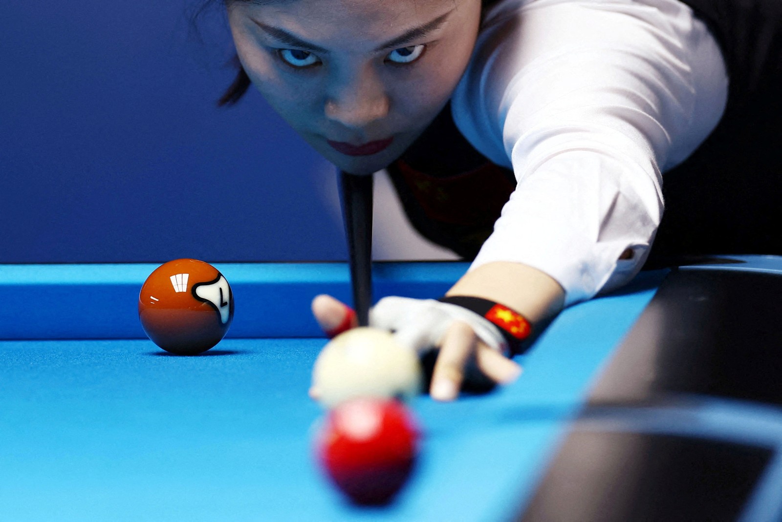 A low image of a pool player lining up a shot.