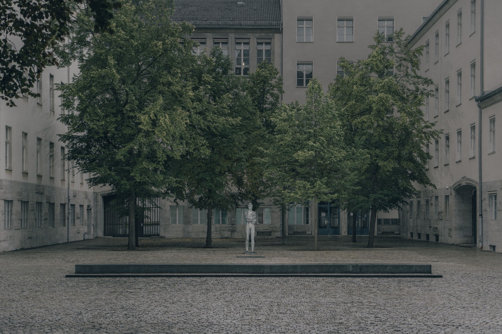 photo of a statue in an austere courtyard with trees