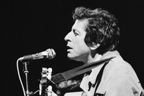 black-and-white photo of man in profile singing into microphone and playing guitar