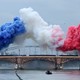 blue, white, and red plumes of smoke above a bridge over the Seine