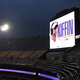 Photograph of an empty stadium at night with a giant screen showing Lane Kiffin's name and photo as head coach of Louisiana State University