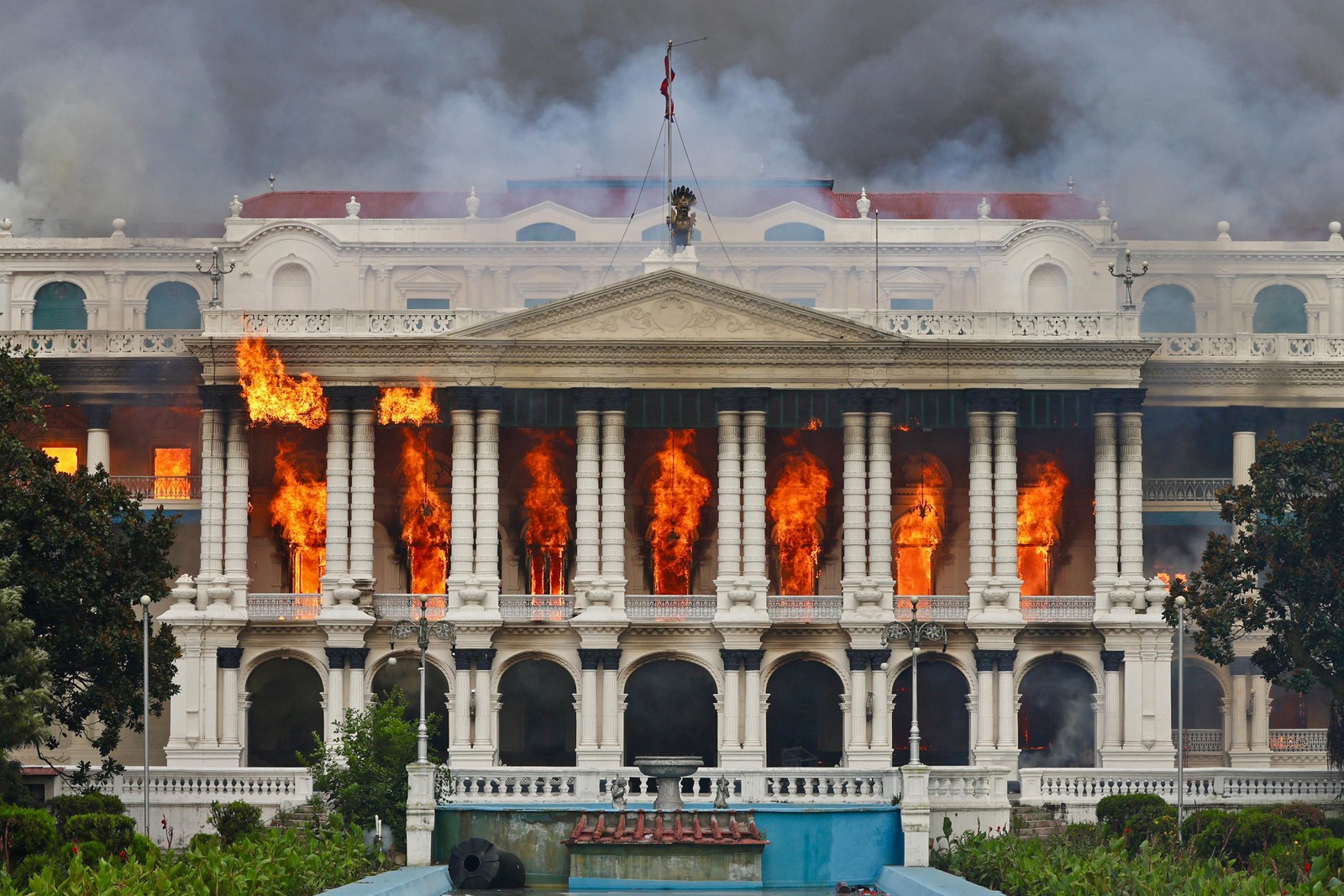 Flames erupt from the portico of a palatial government building.