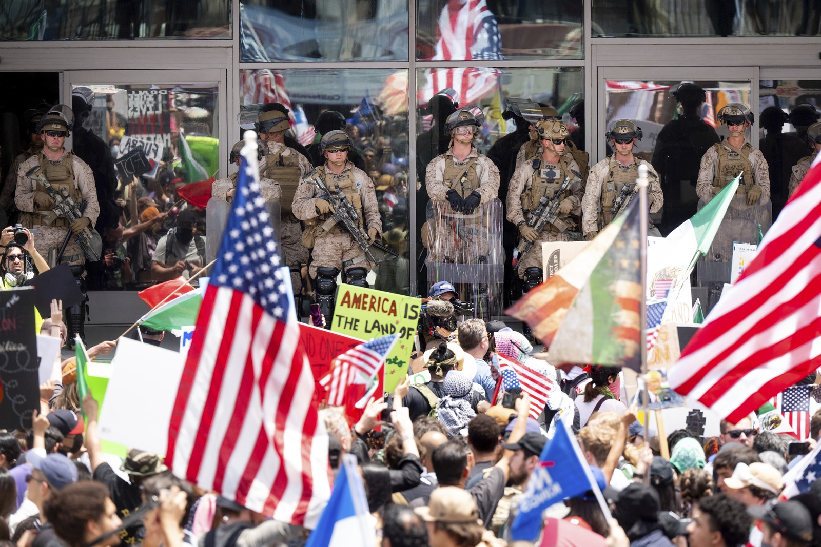 Protesters gather outside a building that is being guarded by a line of United States Marines.